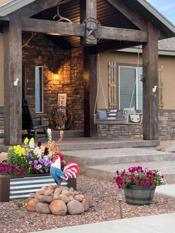 Stone facade entry featuring exposed wood beams, a porch swing, and a decorative light fixture