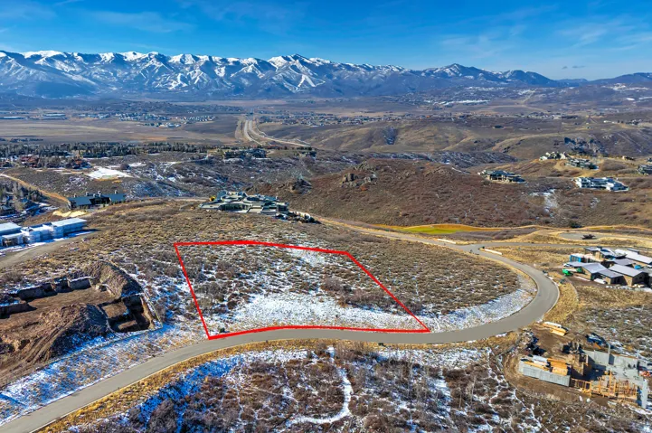 Aerial view of property and surrounding area with property parcel outlined and a mountainous background