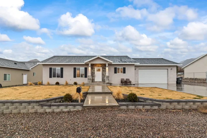 Ranch-style house with stucco siding, stone siding, concrete driveway, a garage, and roof with shingles