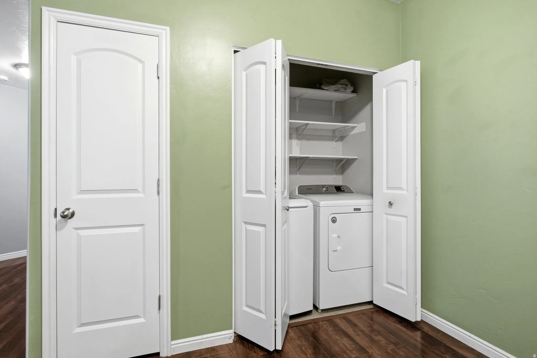 Laundry area featuring baseboards and dark wood-type flooring