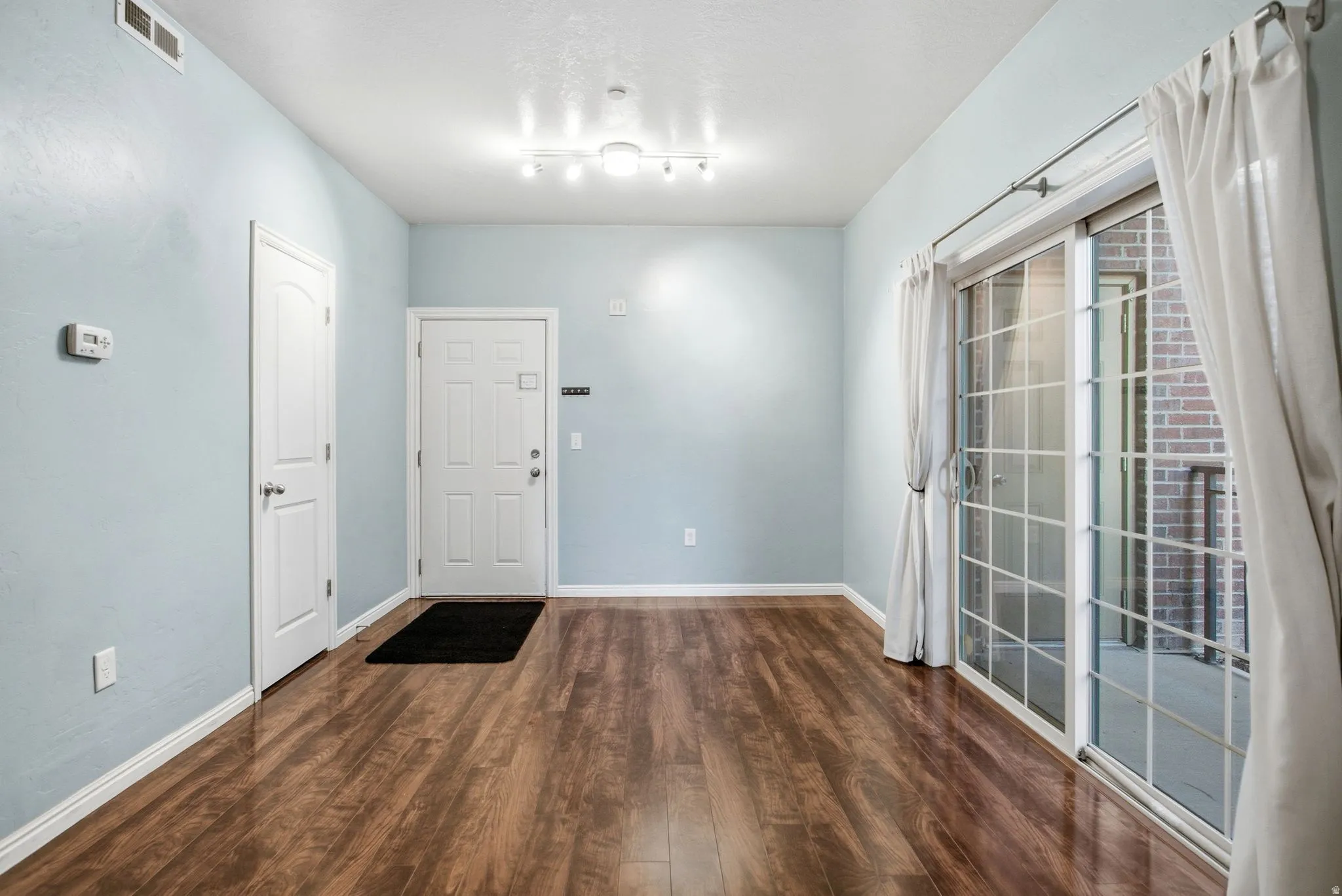 Entrance foyer with dark wood-style flooring and baseboards