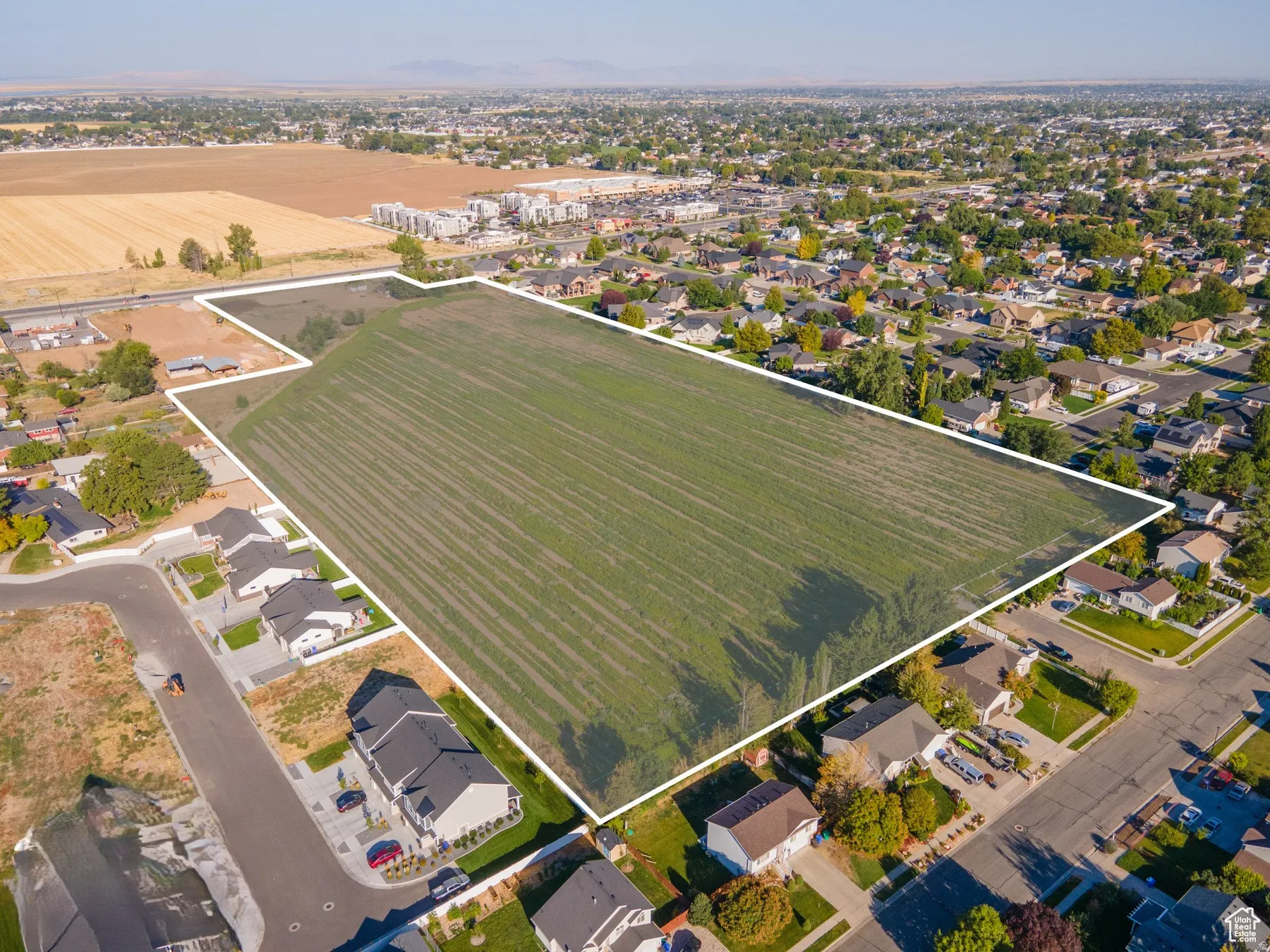 Aerial overview of property's location with property parcel outlined, nearby suburban area, and rural landscape