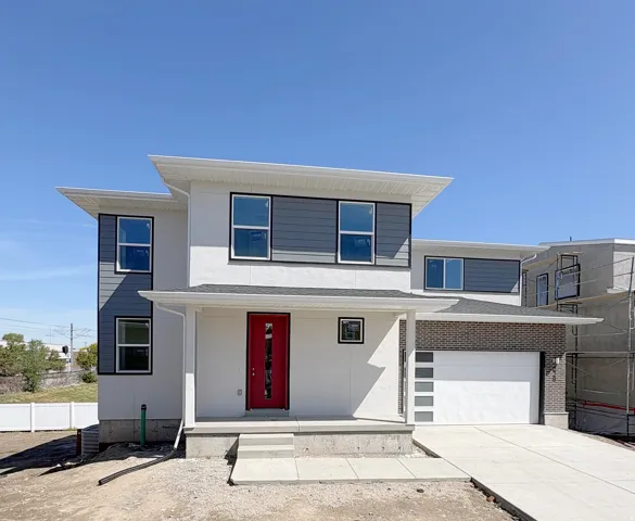 View of front of property featuring a porch, driveway, an attached garage, and stucco siding