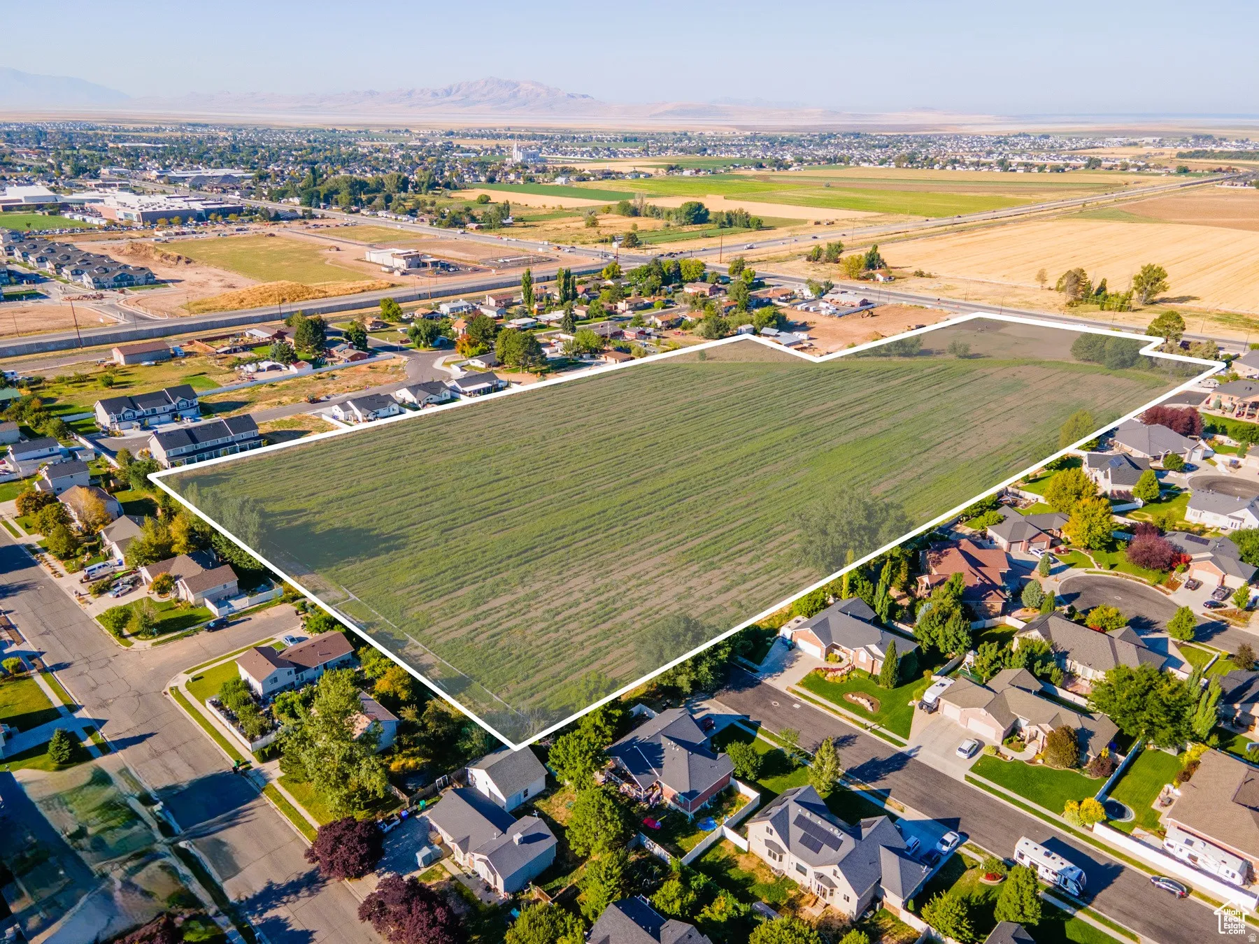 Aerial overview of property's location with property boundaries highlighted, nearby suburban area, and large plots for crops