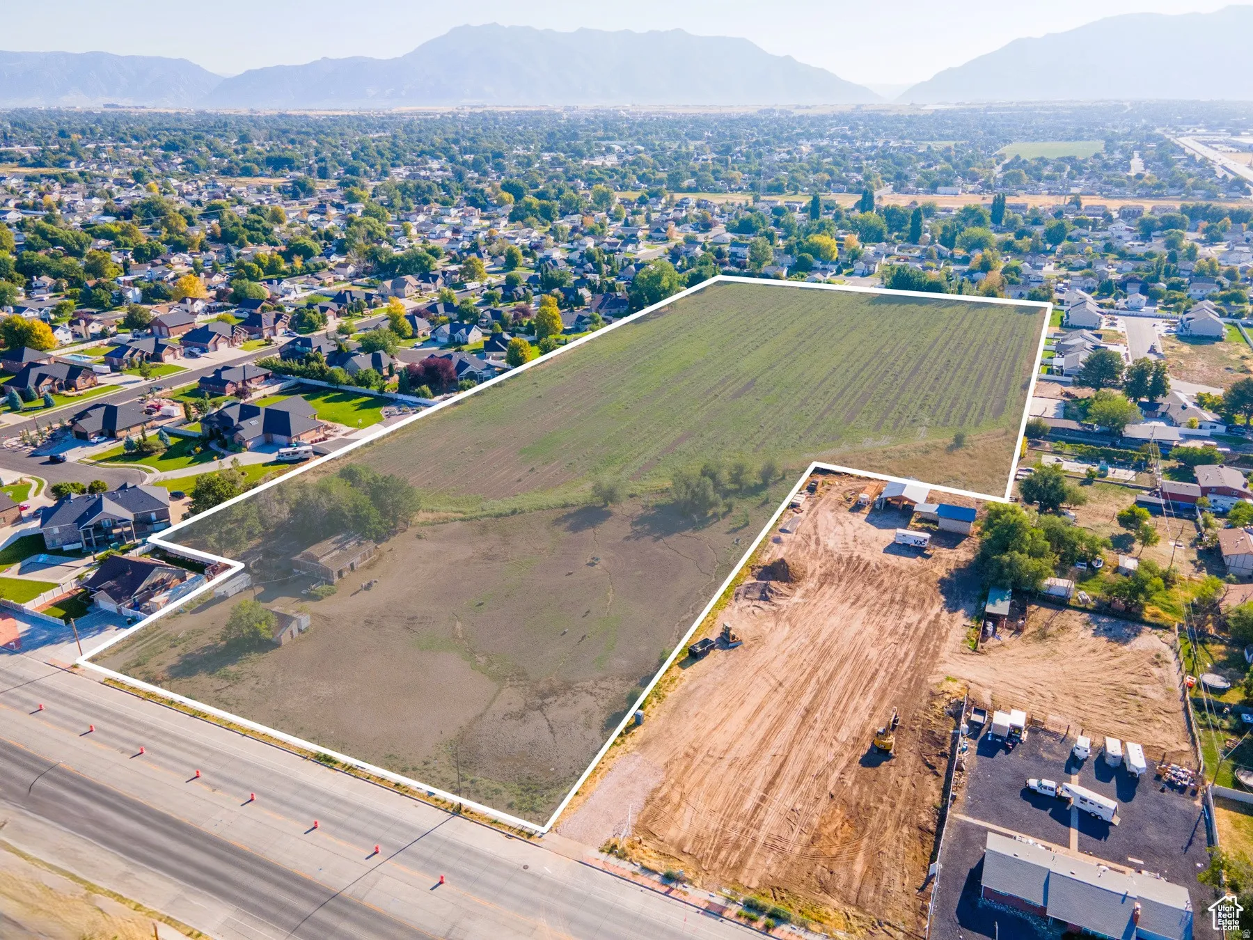 Aerial overview of property's location with property parcel outlined, mountains, and nearby suburban area