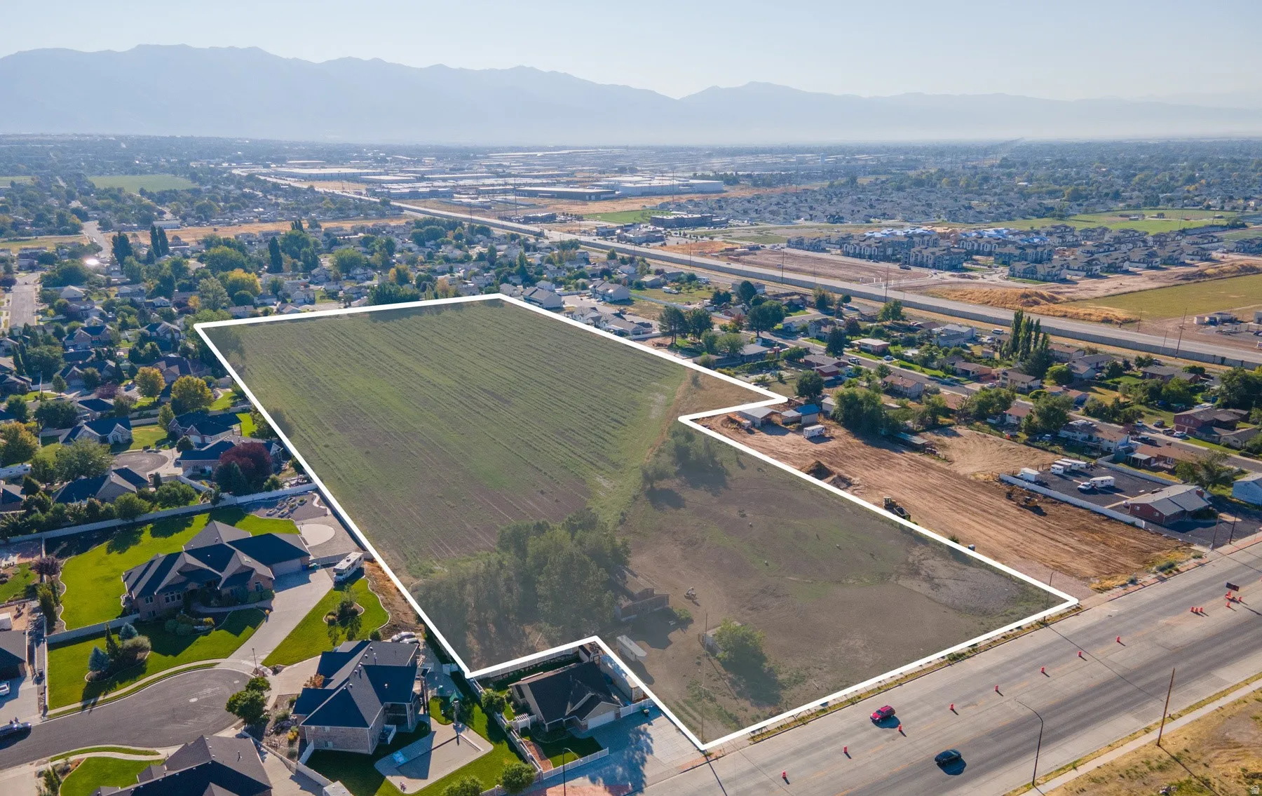 Aerial overview of property's location with property parcel outlined, nearby suburban area, and a mountain backdrop