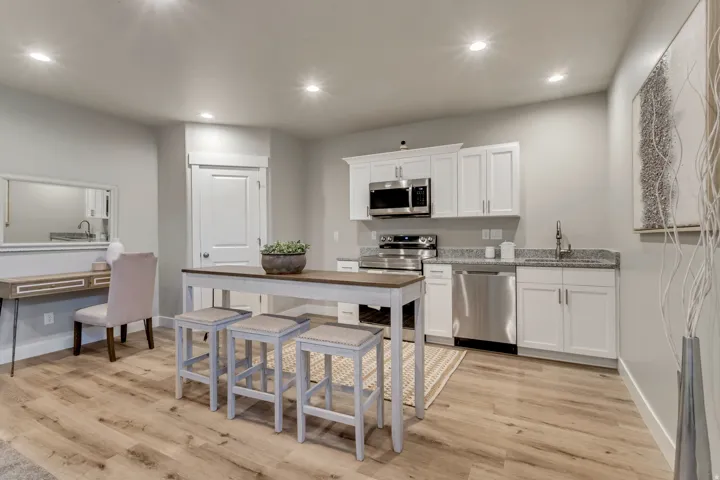 Kitchen with white cabinets, recessed lighting, stainless steel appliances, light stone counters, and light wood-type flooring