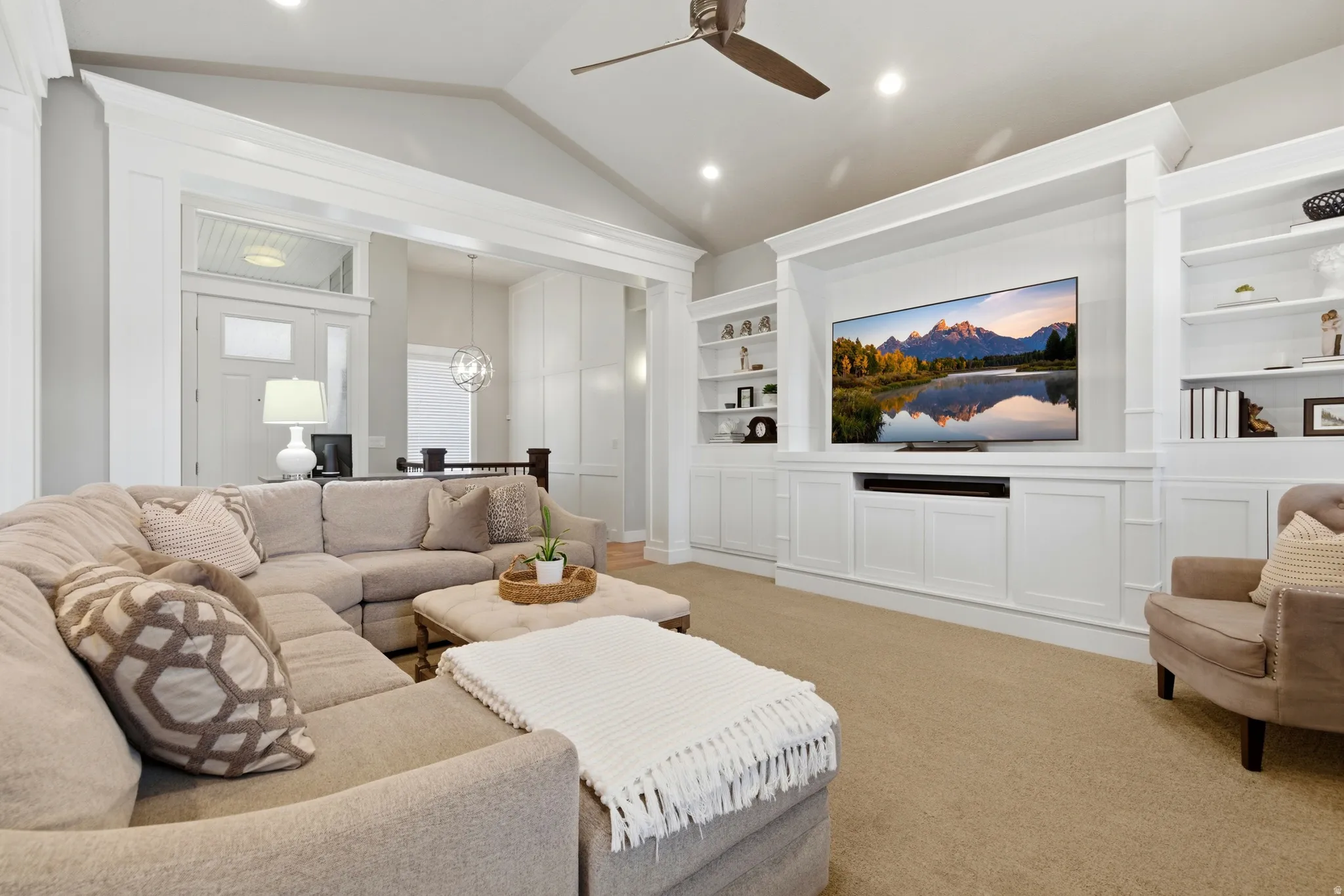 Living room featuring built in features, ceiling fan, light carpet, and suspended lighting