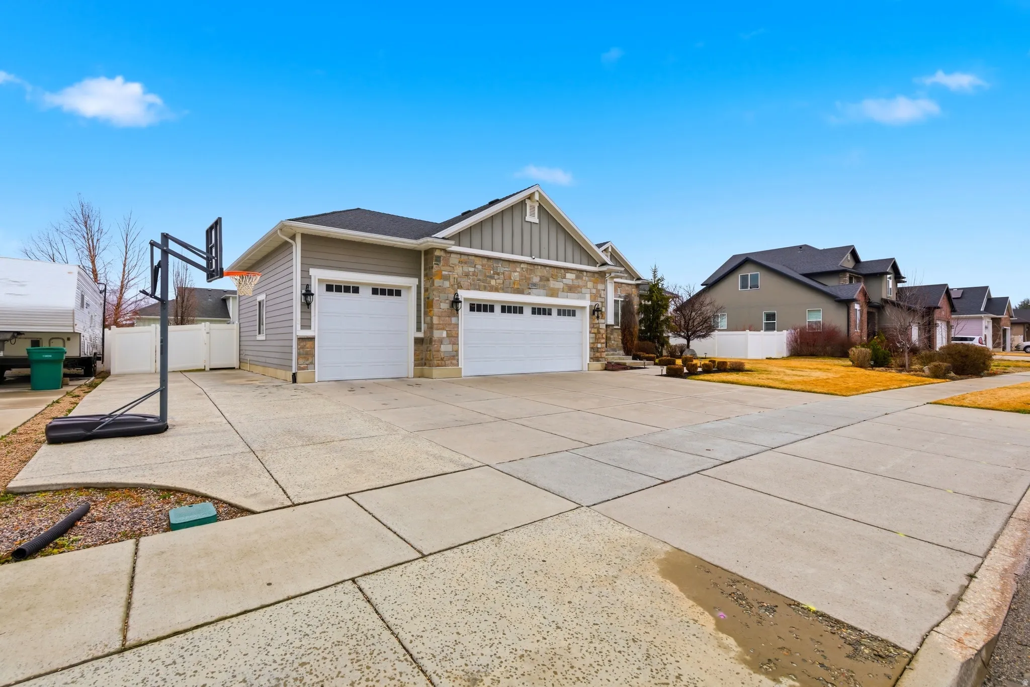 View of home's exterior with board and batten siding, stone siding, driveway, an attached garage, and a residential view