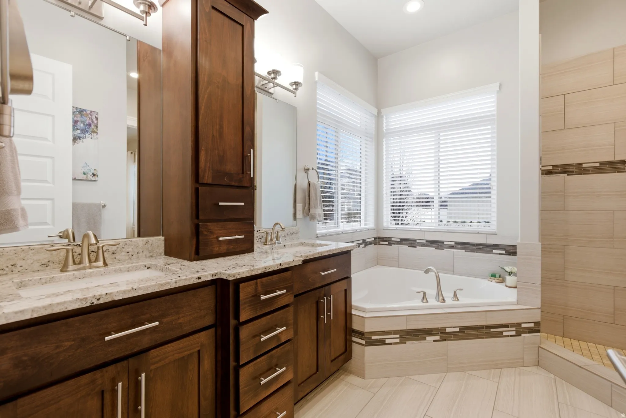 Bathroom with double vanity, a bath, a tile shower, and light tile patterned floors