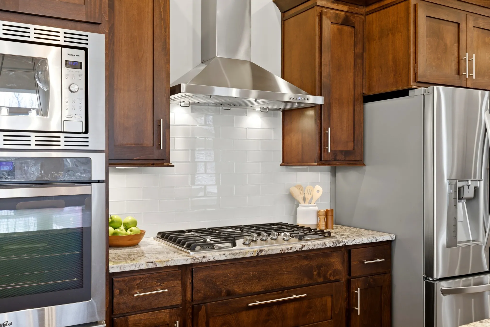 Kitchen featuring stainless steel appliances, light stone countertops, and decorative backsplash