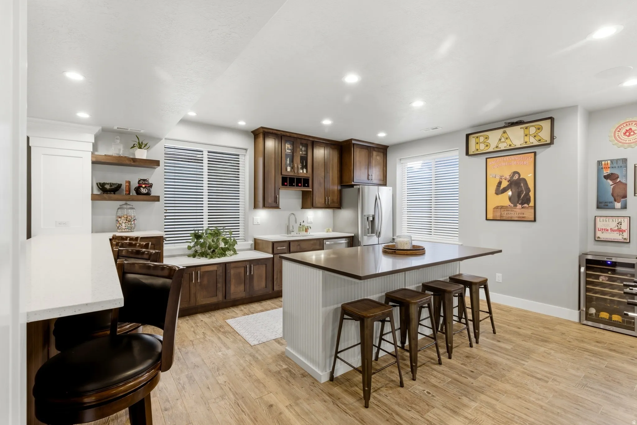 Two tone kitchen featuring a kitchen breakfast bar, two tone cabinetry, wine cooler, light wood-type flooring, and recessed lighting