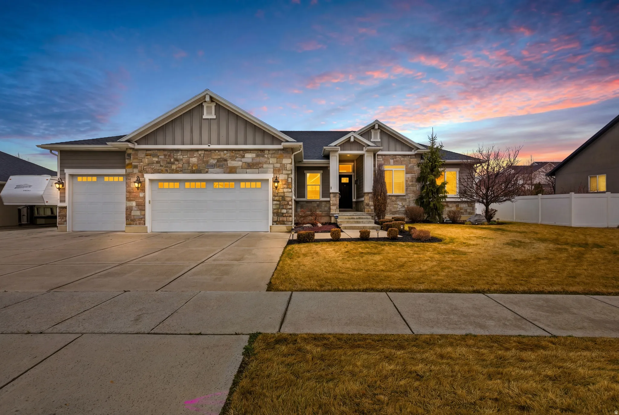 Craftsman-style house with board and batten siding, an attached garage, driveway, and stone siding