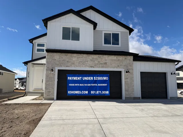View of front of home featuring board and batten siding, stone siding, and driveway