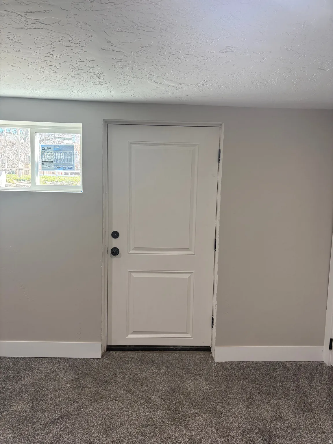 Doorway to outside featuring a textured ceiling and carpet floors