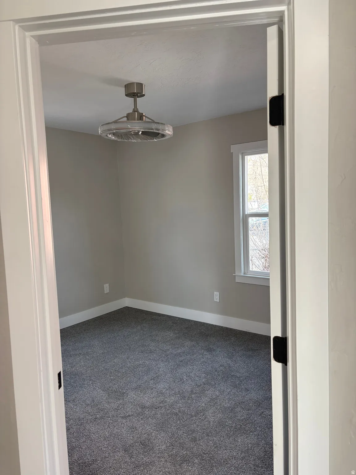 Spare room featuring dark carpet and baseboards