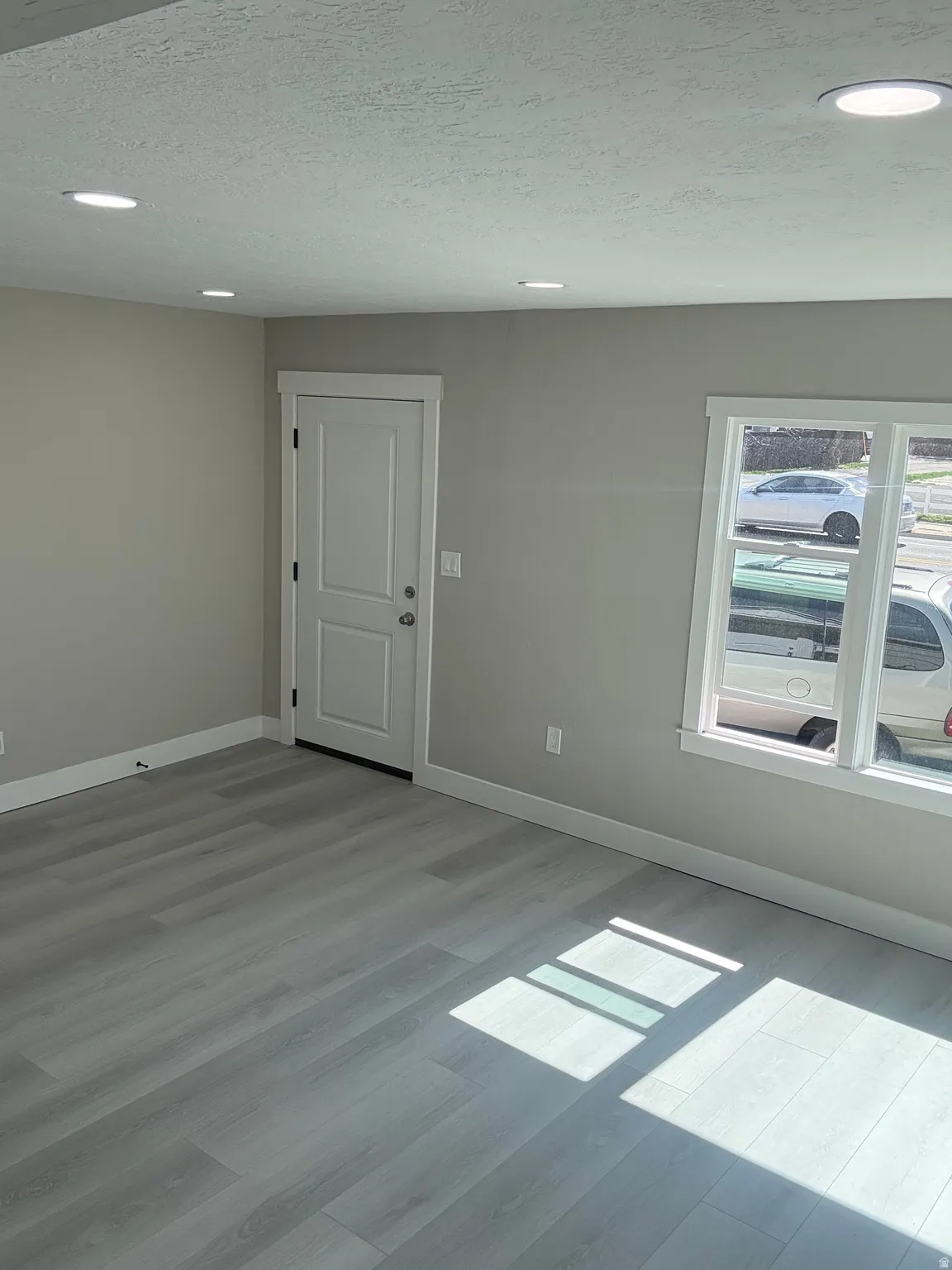 Front entry and living room featuring light laminate floors, a textured ceiling, and recessed lighting