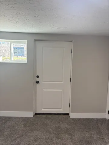 Bedroom 3 Doorway to outside light grey carpet floors and a textured ceiling