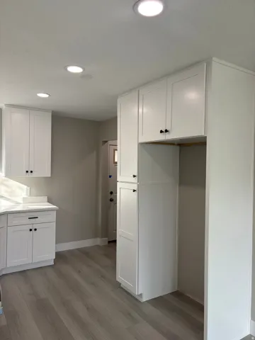 Kitchen with white cabinets, light laminate  floors, and recessed lighting