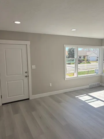 Front entry and living room featuring light laminate floors, a textured ceiling, and recessed lighting