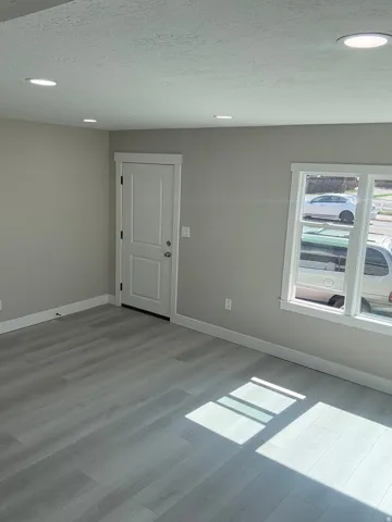 Front entry and living room featuring light laminate floors, a textured ceiling, and recessed lighting