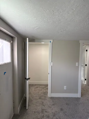 Bedroom 3 walk in closet light grey carpet floors and a textured ceiling
