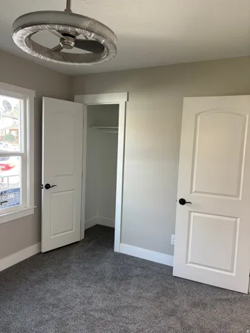 Bedroom 2 closet light colored carpet and a textured ceiling ceiling fan/light