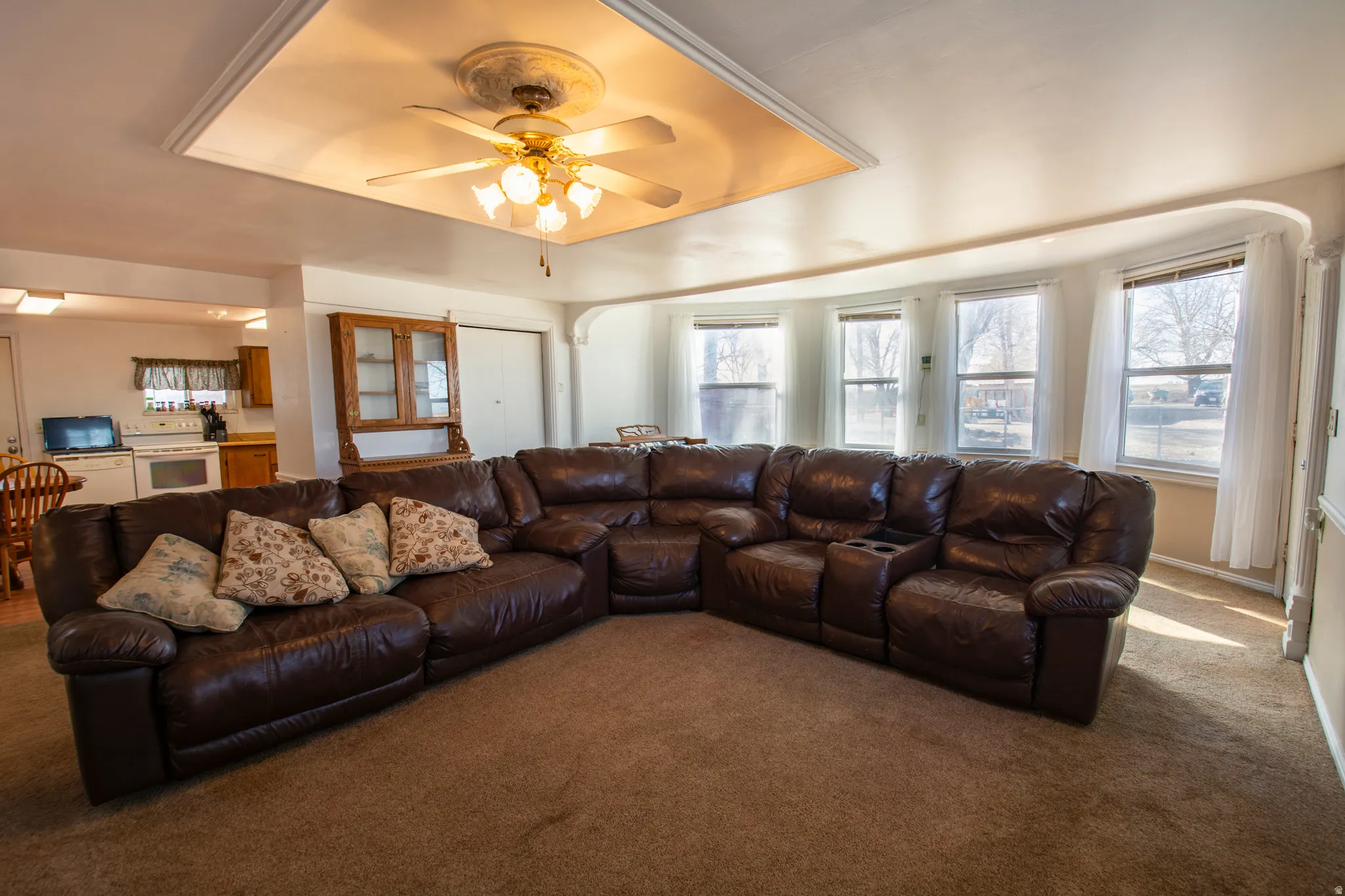 Carpeted living area with a tray ceiling and ceiling fan