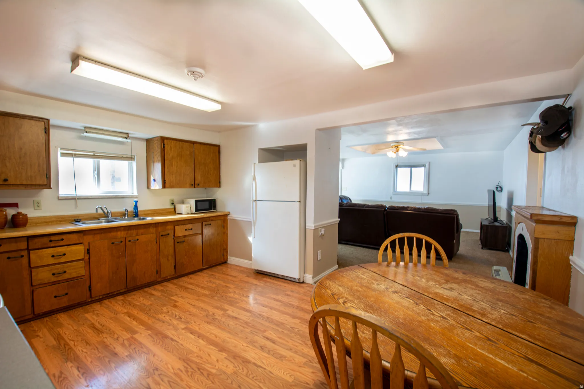 Kitchen featuring wood finish cabinetry, freestanding refrigerator, light countertops, and light wood-style floors