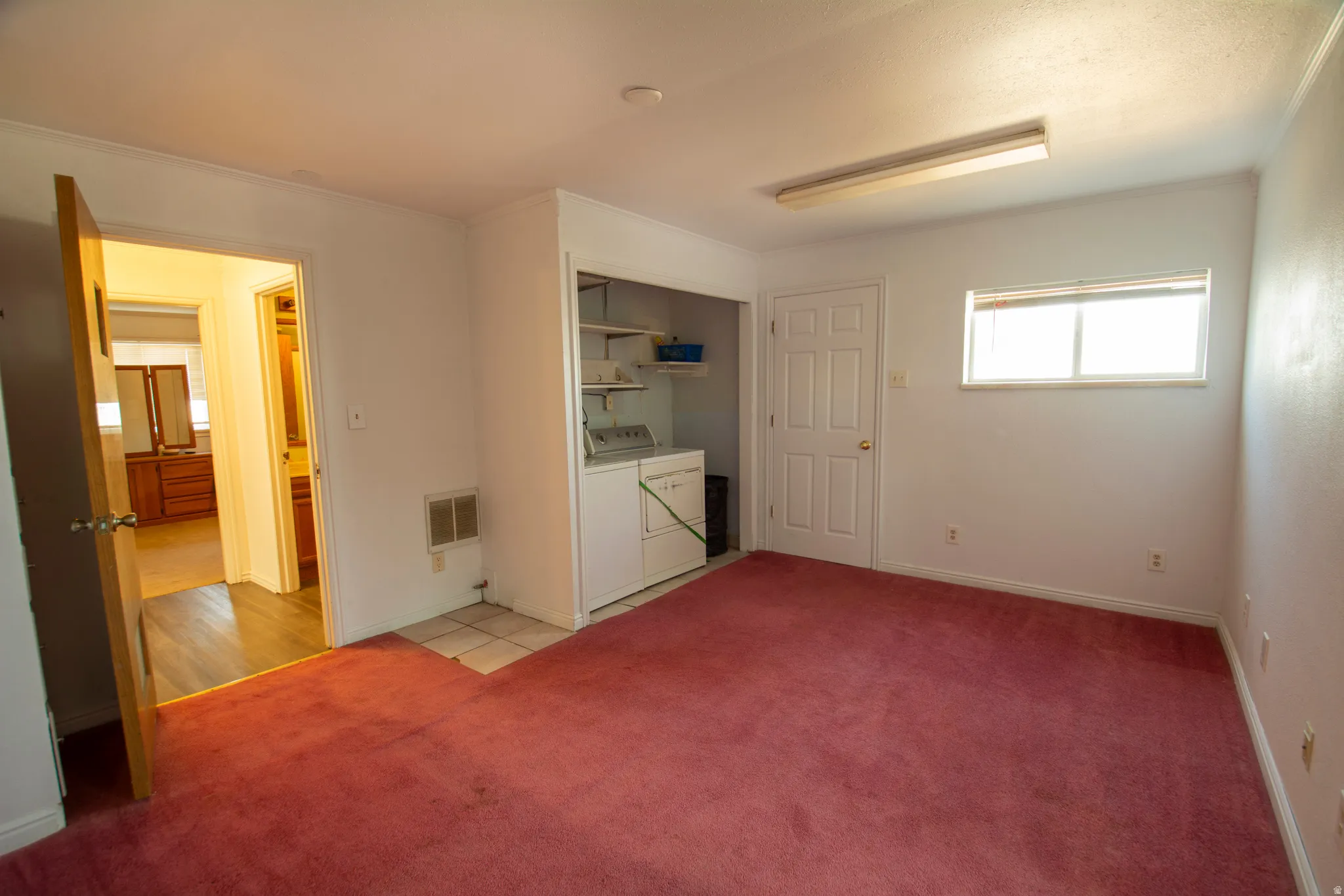 Unfurnished bedroom featuring light carpet, and washer and dryer