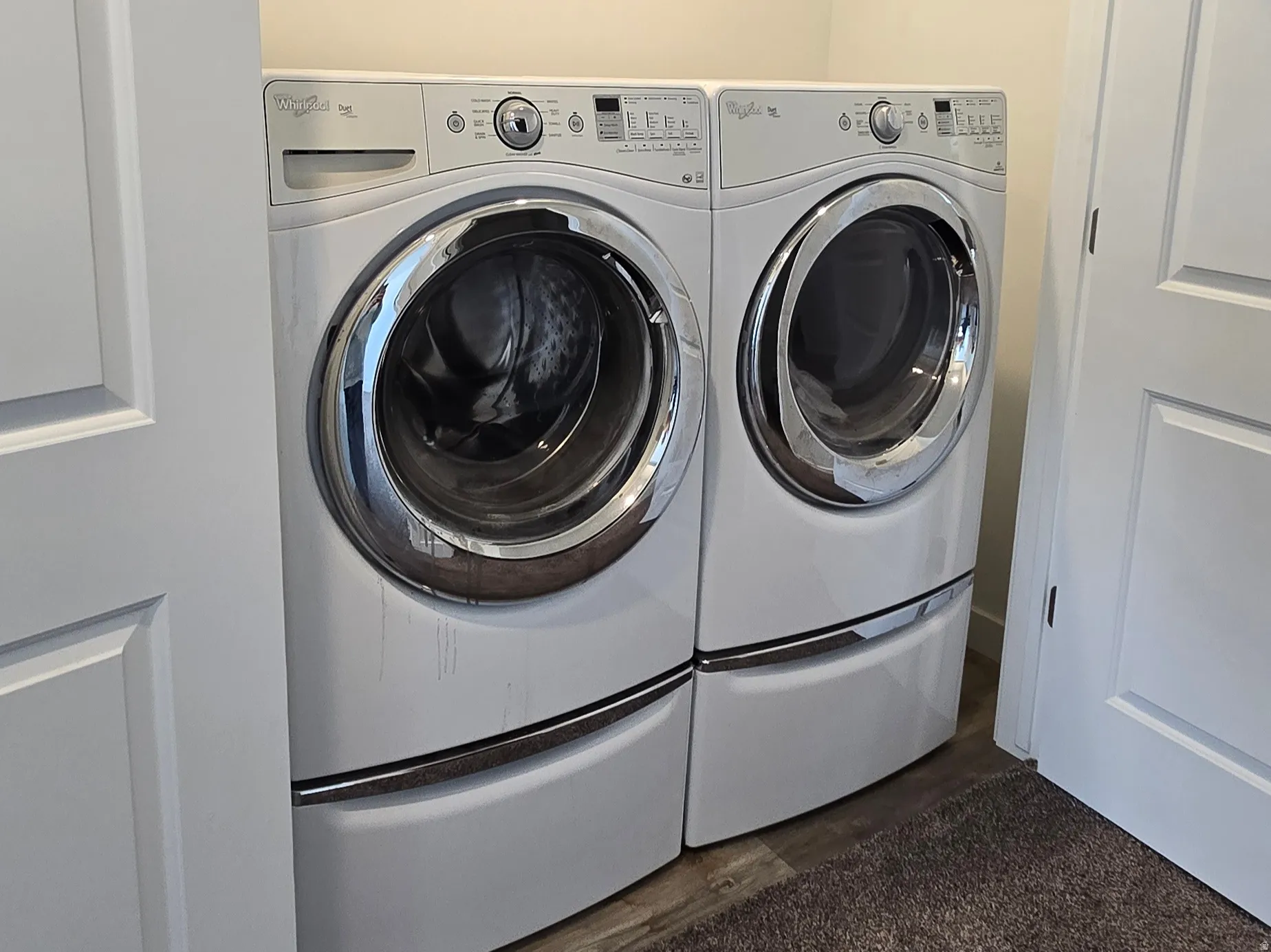 Laundry area featuring dark colored carpet and washing machine and dryer