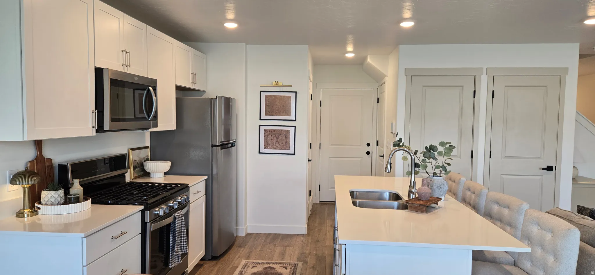 Kitchen featuring a kitchen island with sink, stainless steel appliances, a kitchen bar, white cabinetry, and recessed lighting