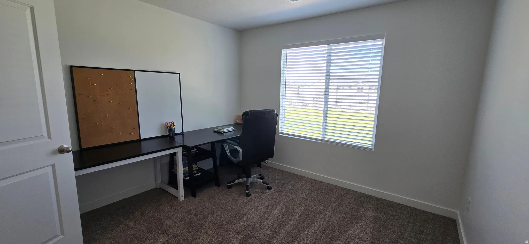 Home office featuring dark carpet and baseboards