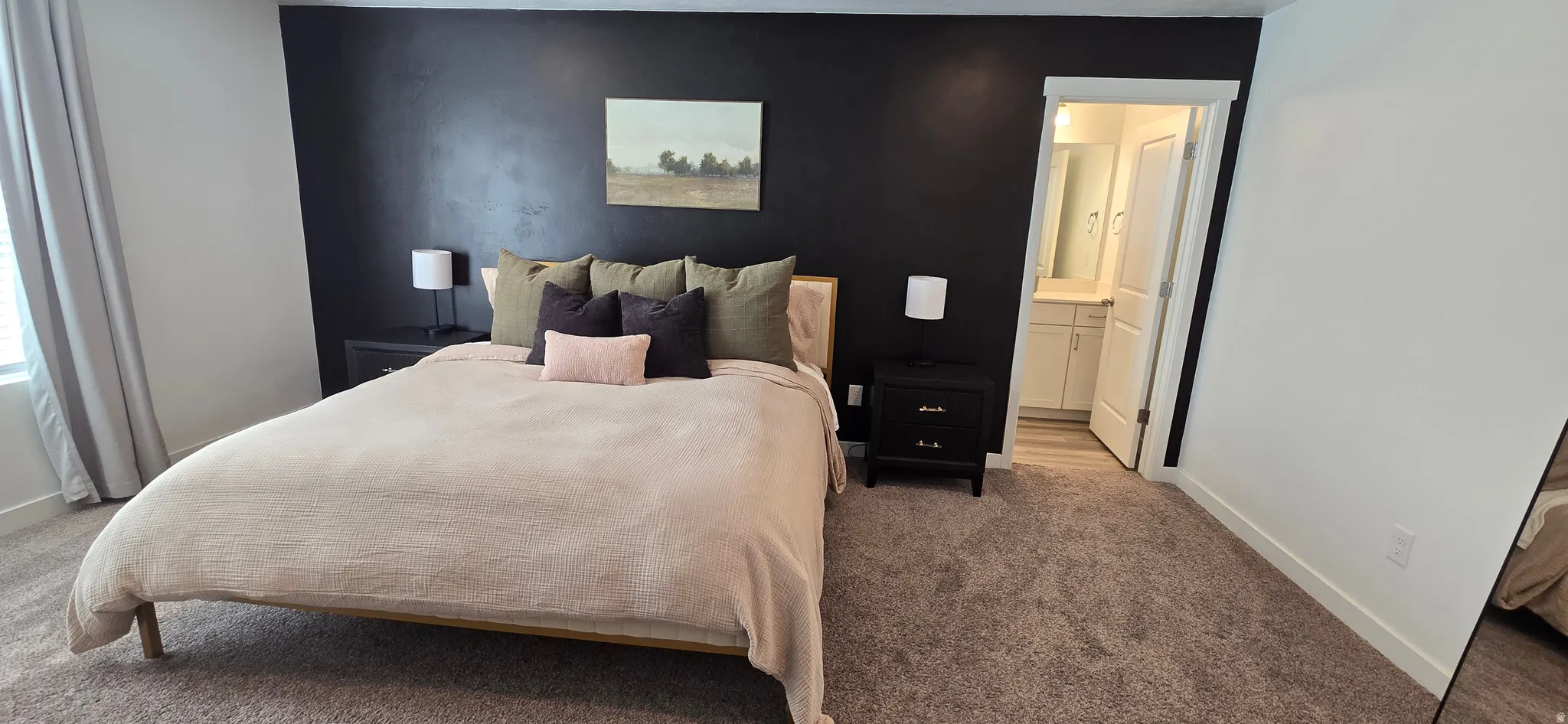 Bedroom featuring carpet, connected bathroom, and an accent wall