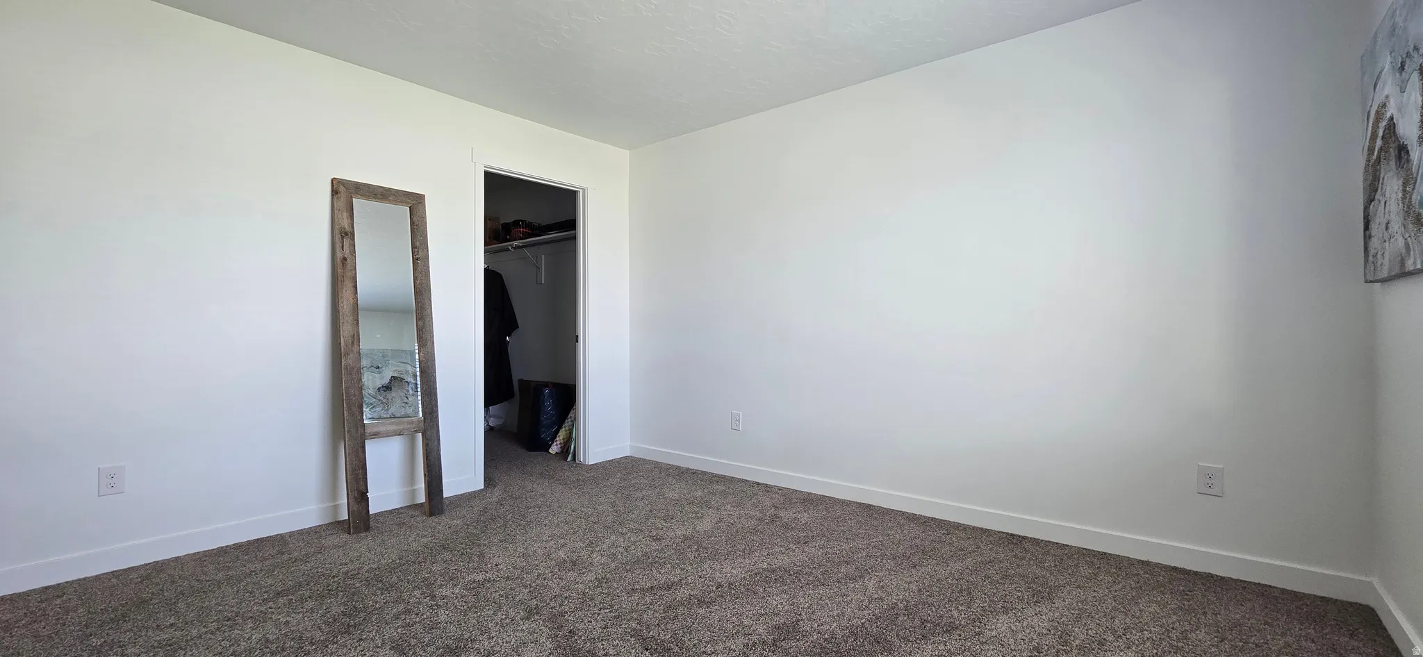 Unfurnished bedroom with dark carpet and a walk in closet