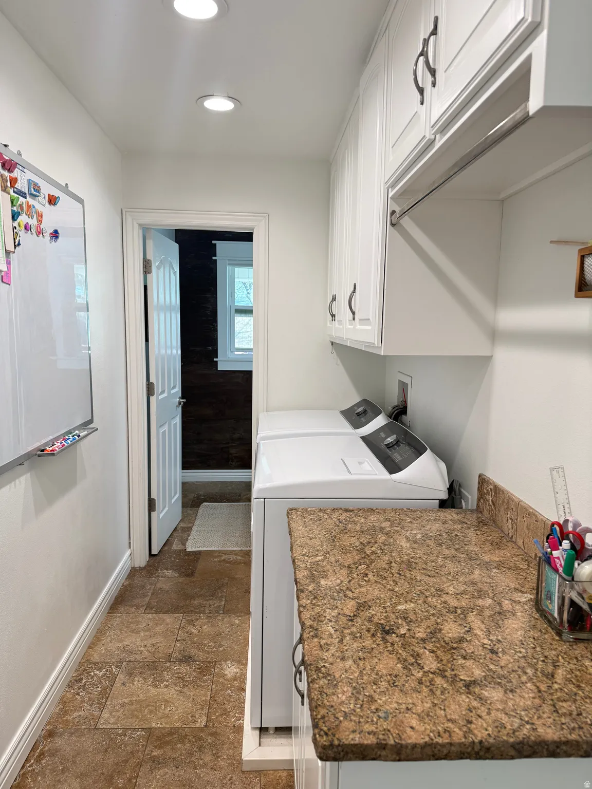 Laundry area with cabinet space, dark stone finish floors. Washer & Dllryer excluded.