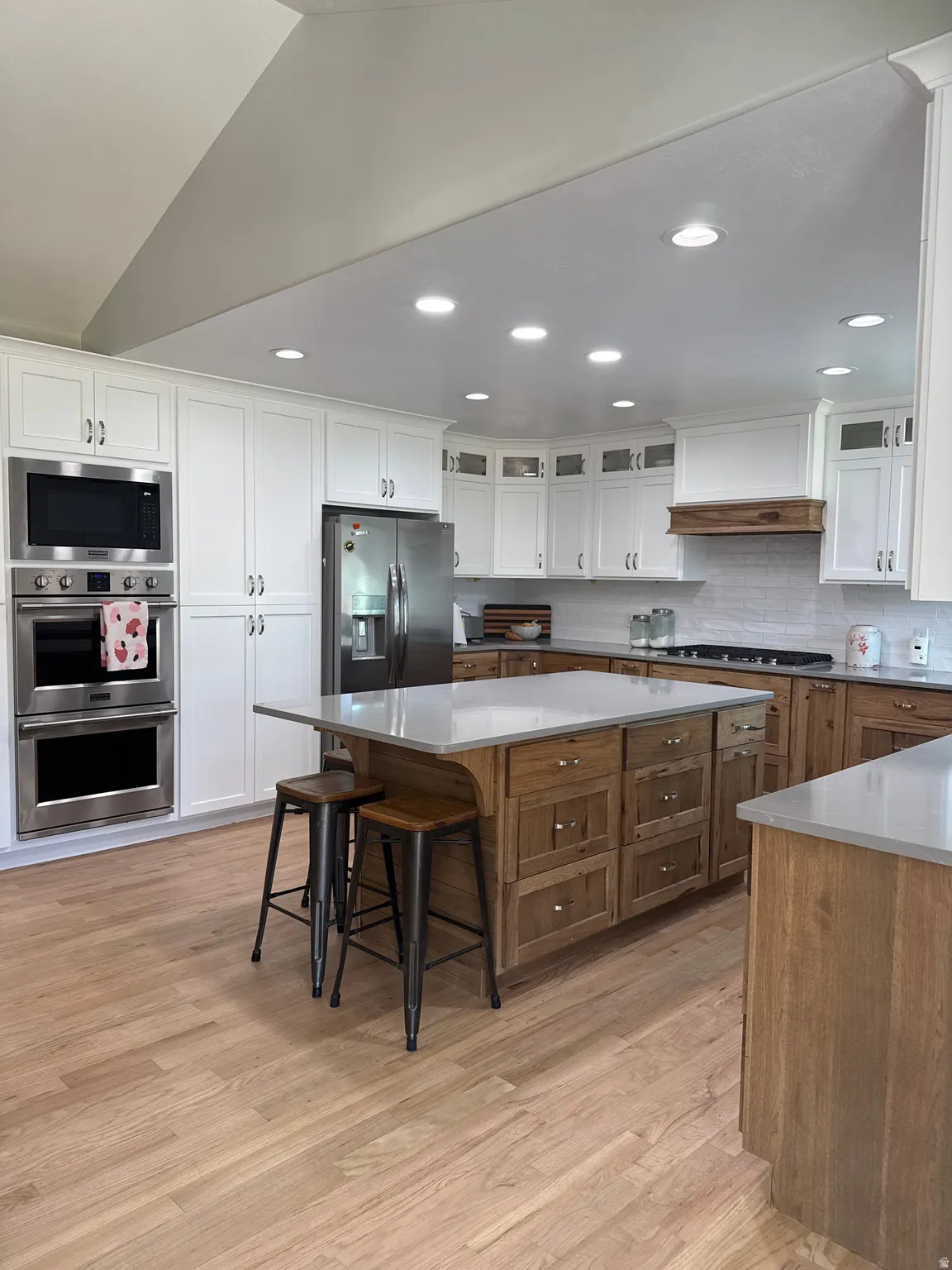 Kitchen featuring an upgraded double oven, microwave, refinished hardwood floors (2026), upgraded gas range, hickory cabinets, a new island, and recessed lighting.