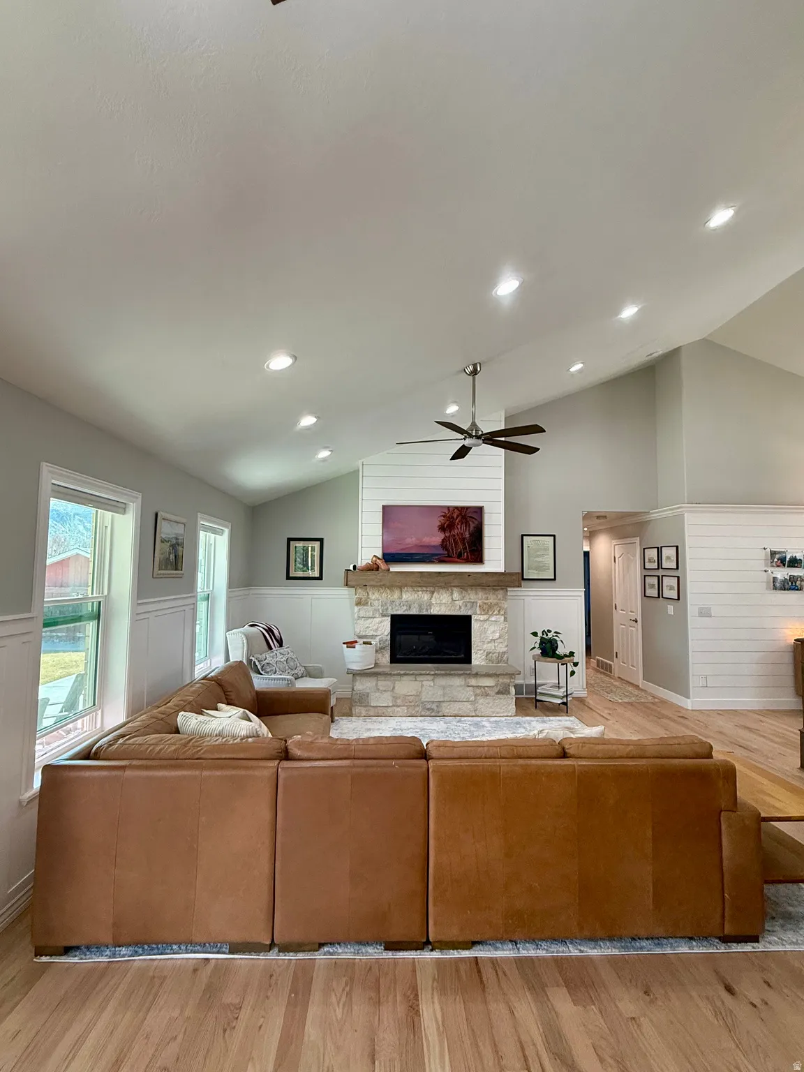 Living area featuring vaulted ceiling, a stone fireplace, and recently refinished hardwood floors.