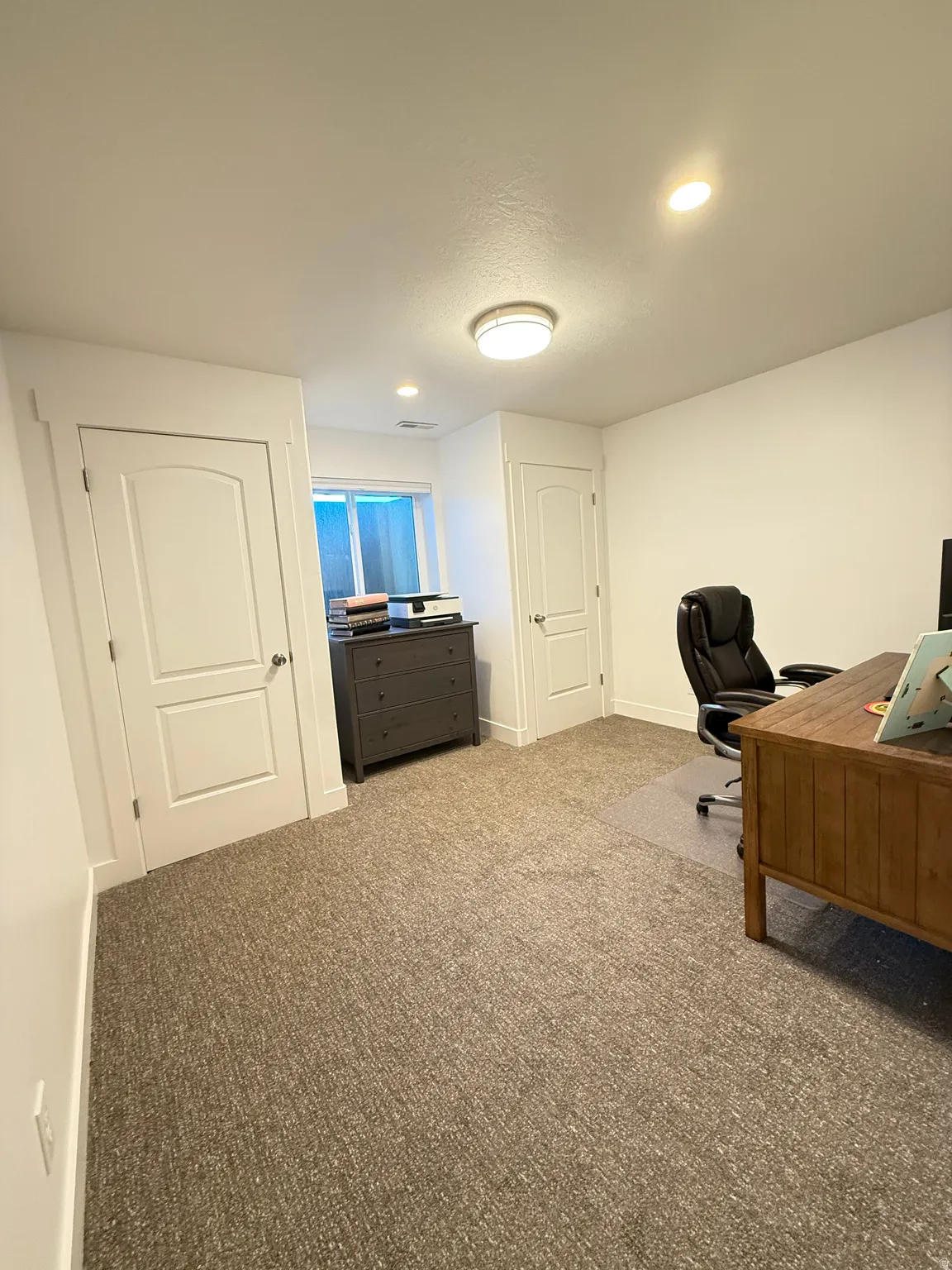 Bedroom 6 with updated carpet, closet doors, paint, and windows, currently used as a home office.