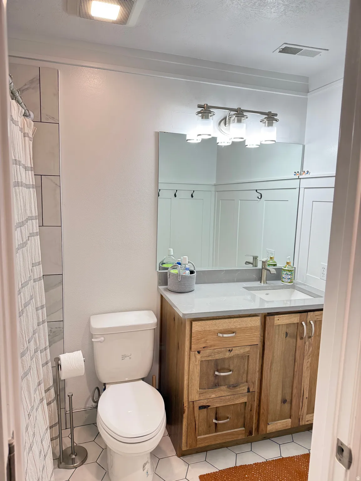 Full bath with upgraded vanity, fixtures, toilet, flooring, and quartz countertops.