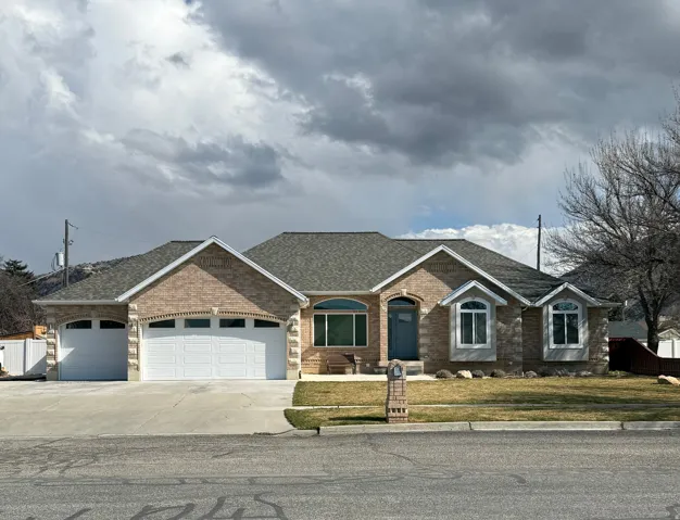 View of front of property featuring a three car garage, brick siding, and recently re-shingled roof.