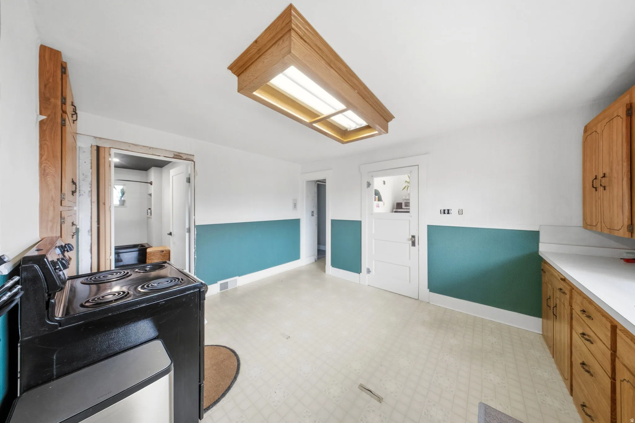 Kitchen featuring light flooring, light countertops, black electric range oven, and wood finish cabinetry