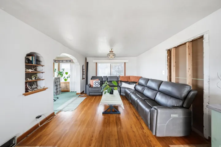 Living area featuring arched walkways and wood finished floors