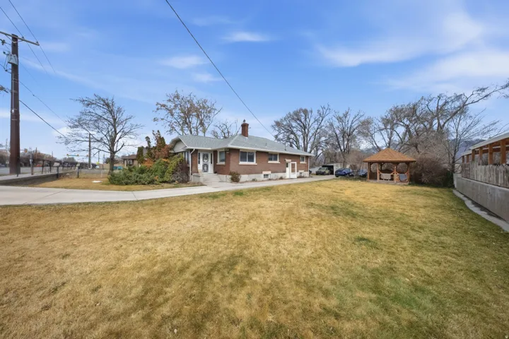 Rear view of property with a gazebo, a chimney, and brick siding