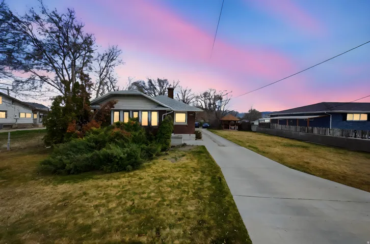 View of front of house featuring brick siding, a chimney, a residential view, and concrete driveway