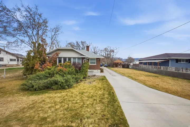 View of front of property with brick siding, a chimney, concrete driveway, and a residential view