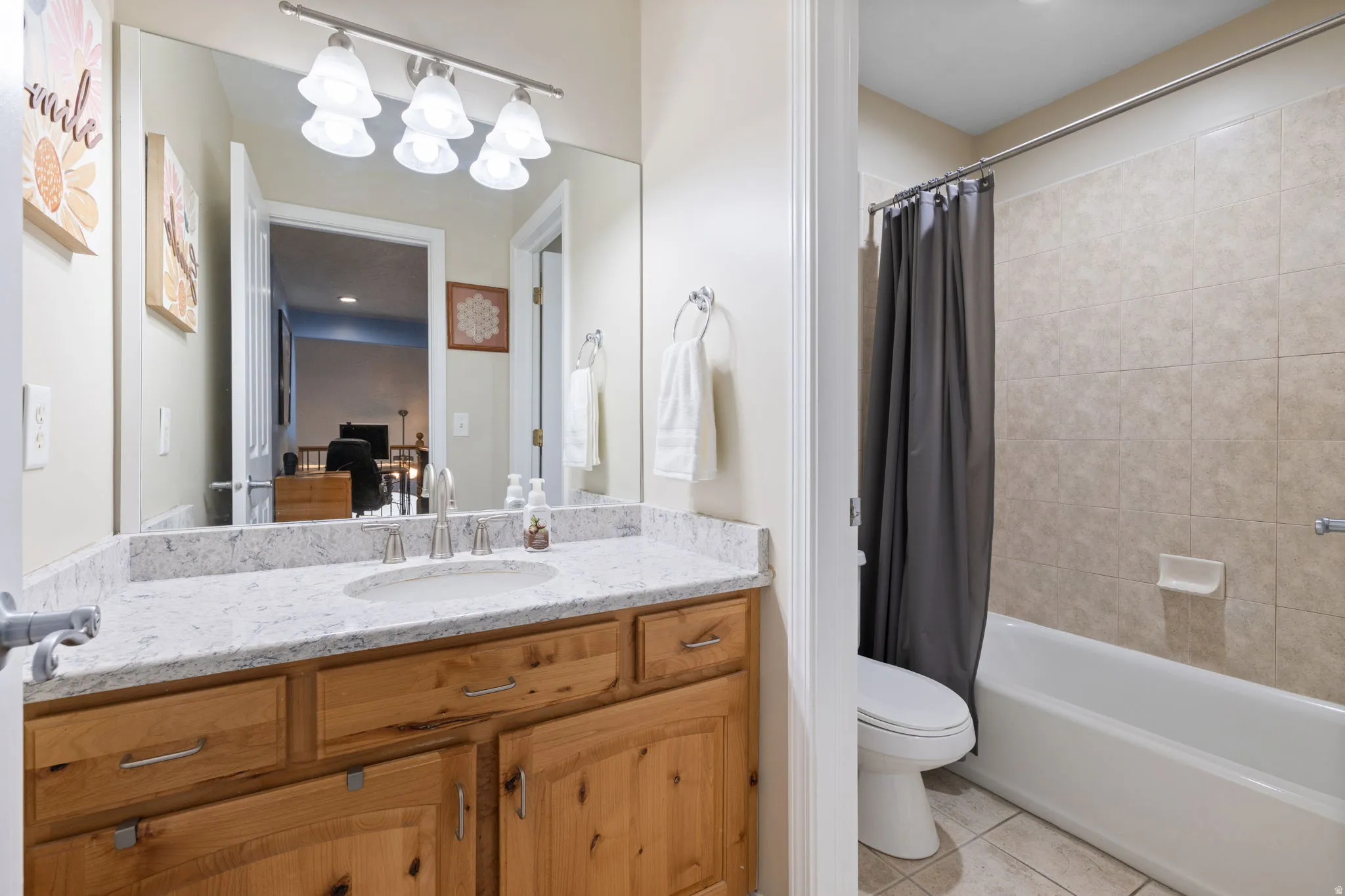 Full bath with vanity, shower / bath combo with shower curtain, and light tile patterned flooring