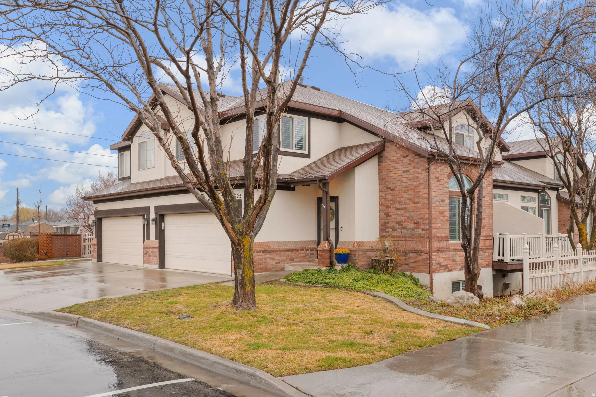 Traditional-style townhouse featuring brick siding, driveway, an attached garage, stucco siding, and roof with shingles