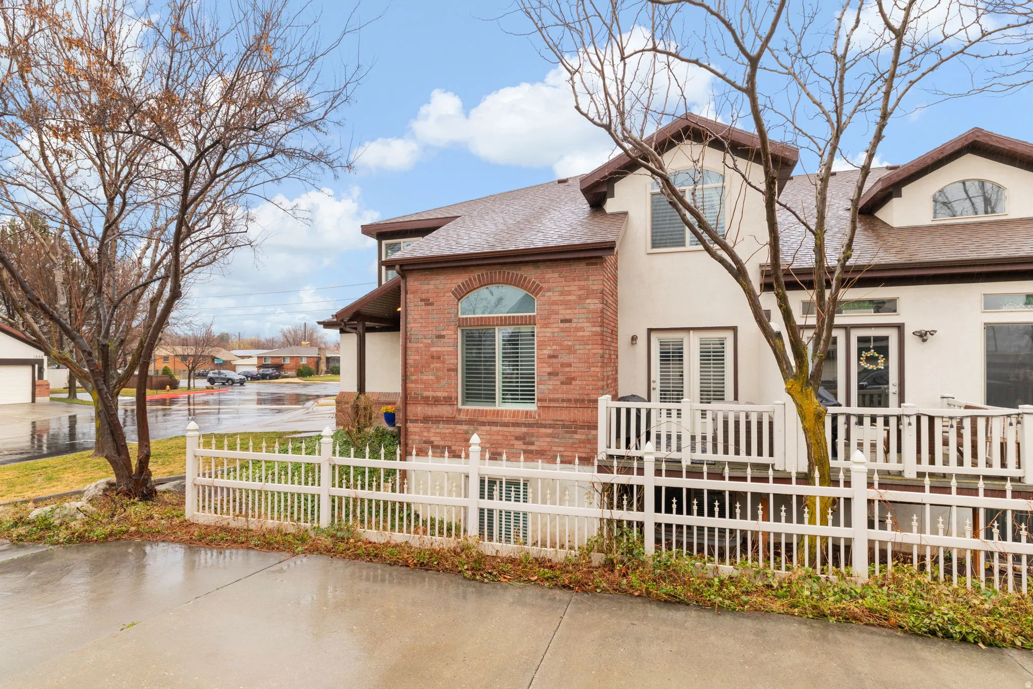 View of front of property featuring brick siding, a fenced front yard, and a shingled roof