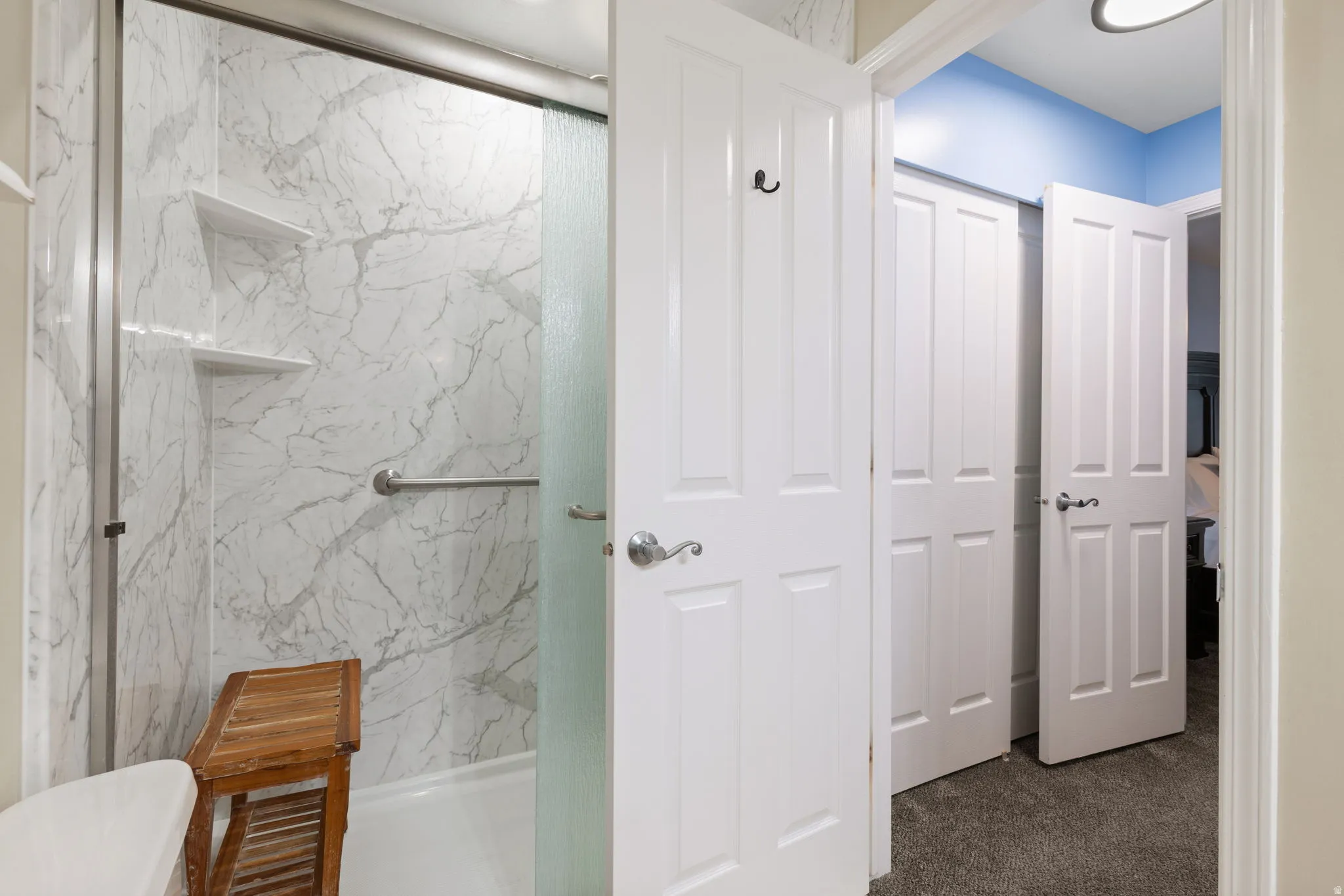 Primary Bathroom with a marble finish shower and dark carpet